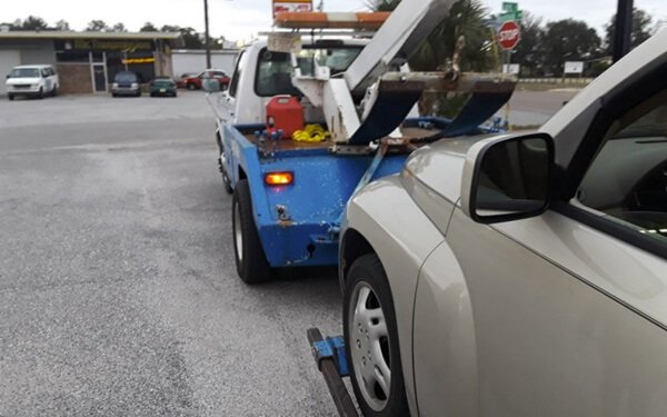 Blue tow truck pulling a brown car