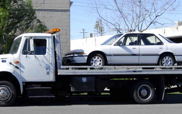 White flatbed tow truck with white car